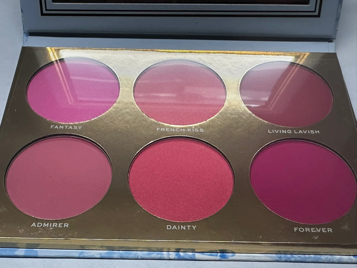 Makeup palette with pink shades labeled 'Fantasy', 'French Kiss', etc.